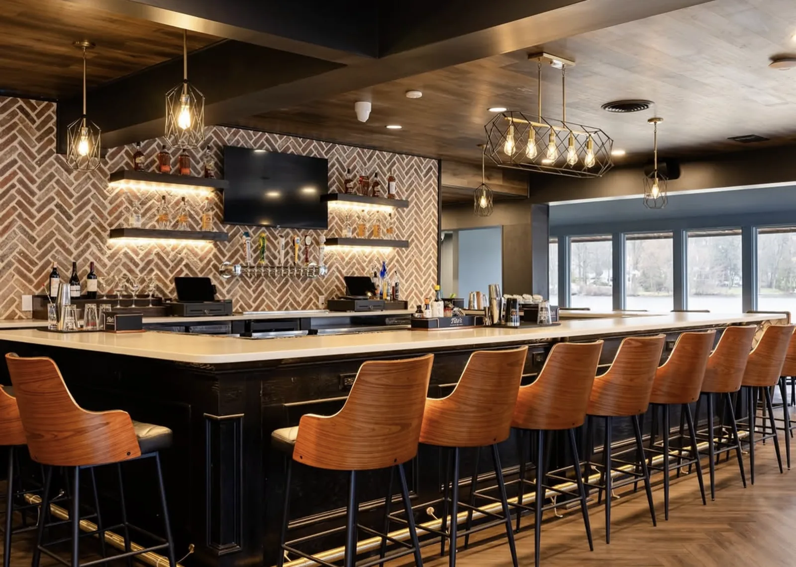 The main bar at Lake Drive Tavern with herringbone tile, pendant lights and windows onto Packanack Lake